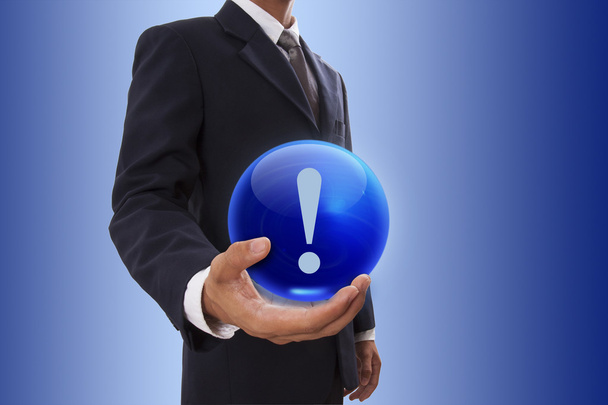 Empresario mano sosteniendo bola de cristal azul con signo de signo de exclamación
. - Foto, Imagen
