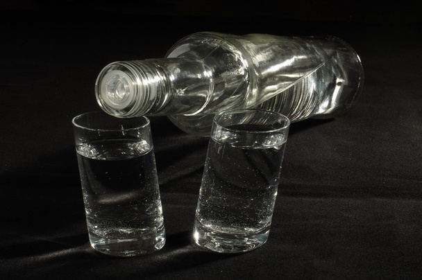 Бутылка водки и два стакана под низким углом
 - Фото, изображение
