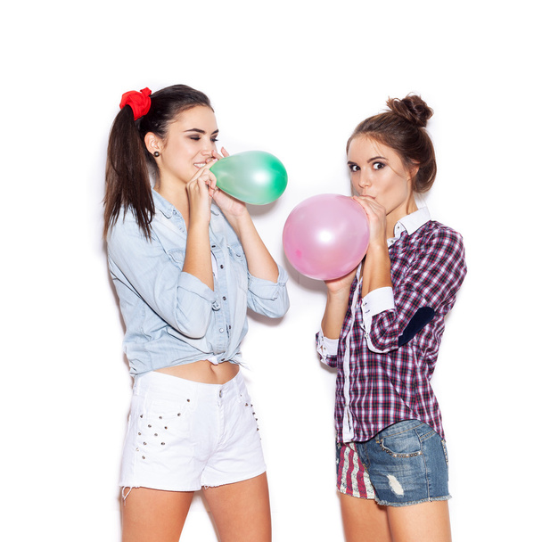 Two happy girls inflate colored balloons - Фото, изображение