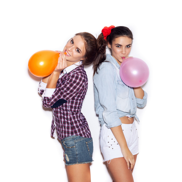 Twee vriendinnen opblazen gekleurde ballonnen - Foto, afbeelding