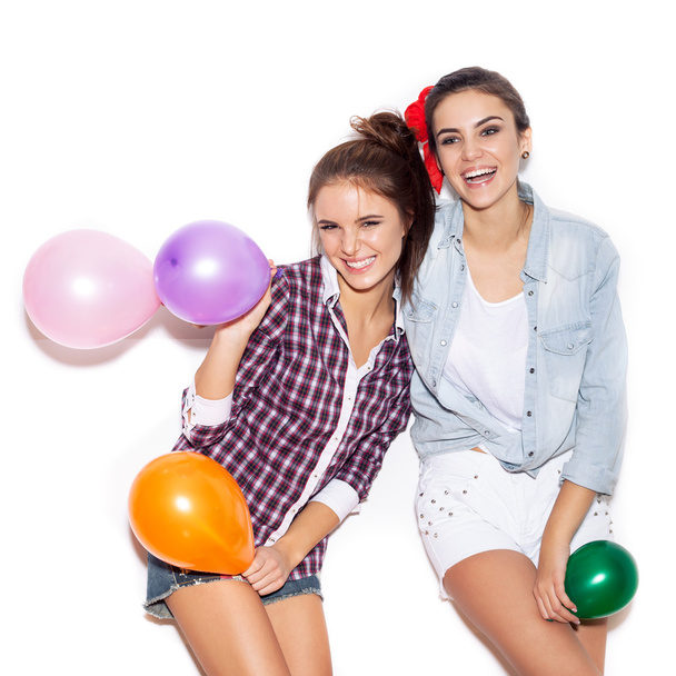 Two happy girls smiling and holding colored balloons - Φωτογραφία, εικόνα