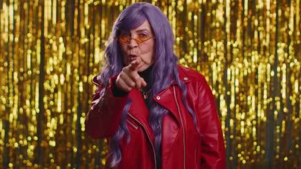 I choose you. Stylish woman with purple hair pointing to camera and looking with playful happy expression, making choice, showing direction. Senior elderly grandmother on shiny disco party background - Footage, Video