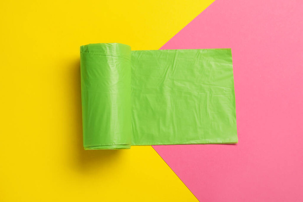 Roll of green garbage bags on color background, top view - Photo, Image
