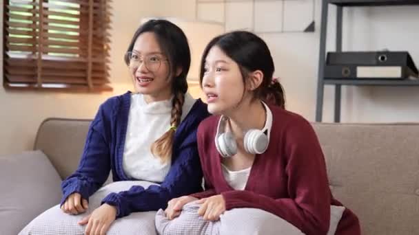 Twee jonge vrouw juichen samen voor sport op tv in gezellige woonkamer thuis. - Video