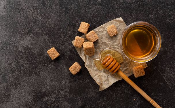 Brown sugar with honey and wooden honey dipper on stone background. Image of beauty. View from above. - Φωτογραφία, εικόνα
