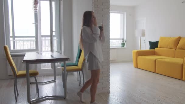 Молода збуджена жінка в легкому одязі п'є каву в своїй квартирі і починає танцювати. Середній постріл
 - Кадри, відео