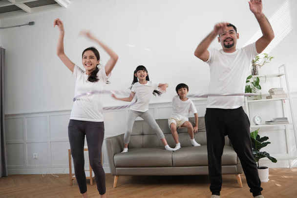 Happy wellness aasialainen thaimaalainen perhe, vanhemmat ja lapset ovat hauskoja hulavanteita yhdessä, kuntoilua ja terveellistä liikuntaa valkoisessa olohuoneessa, kotimaisessa elämäntavassa ja viikonlopun toiminnassa.. - Valokuva, kuva
