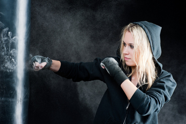 Blond boxing woman in black punching bag - Foto, afbeelding