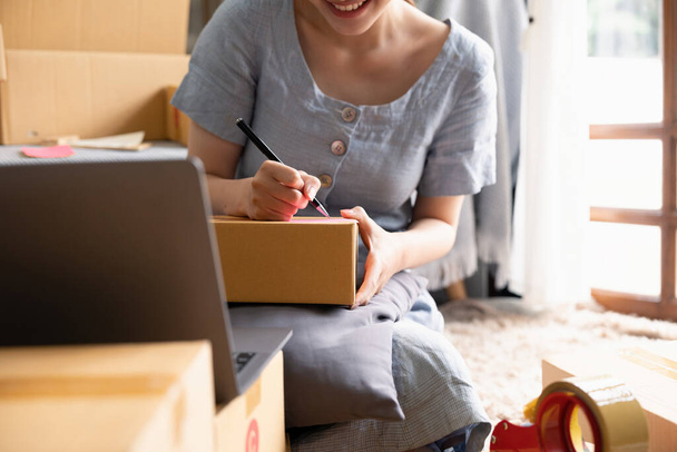 Small businesses SME owners female entrepreneurs writing address on receipt box and check online orders to prepare to pack the boxes, sell to customers, sme business ideas online - Photo, Image