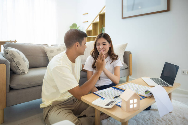 Asian couple in home or house. To compare prices, interest, credit. Include laptop, calculator and document on table. Concept for marriage, loan, finance, insurance, mortgage, real estate and property - Photo, Image