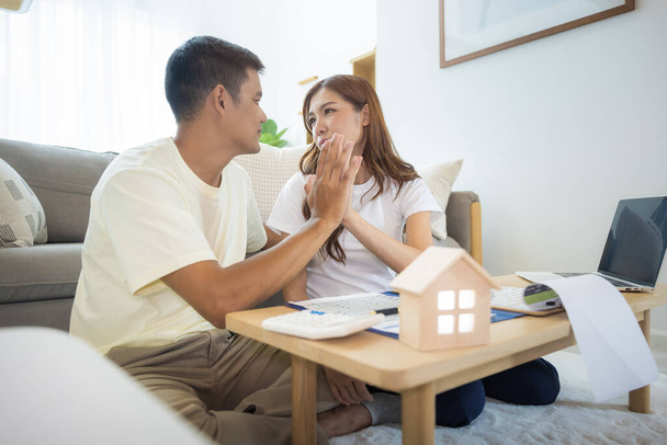 Asian couple in home or house. To compare prices, interest, credit. Include laptop, calculator and document on table. Concept for marriage, loan, finance, insurance, mortgage, real estate and property - 写真・画像