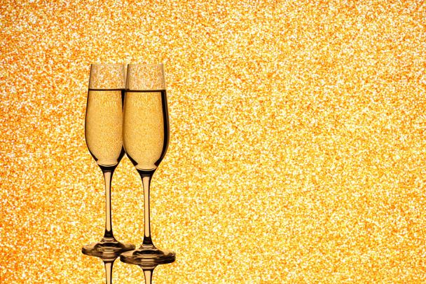 Dwa kieliszki do szampana na niewyraźne złotym tle - Zdjęcie, obraz