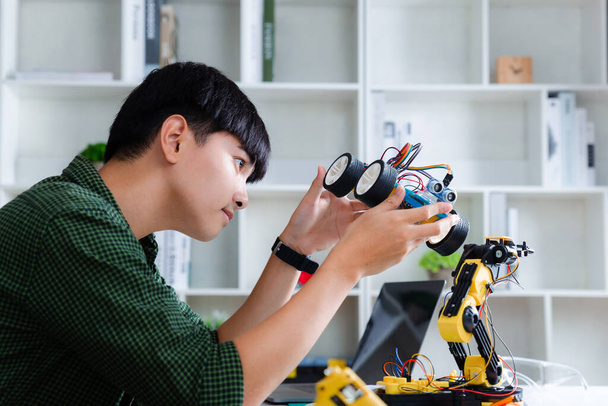 Asyalı genç evde oyuncak araba ev ödevi yapıyor. Robot programlama teknolojisi ve BTMM eğitim konsepti. - Fotoğraf, Görsel