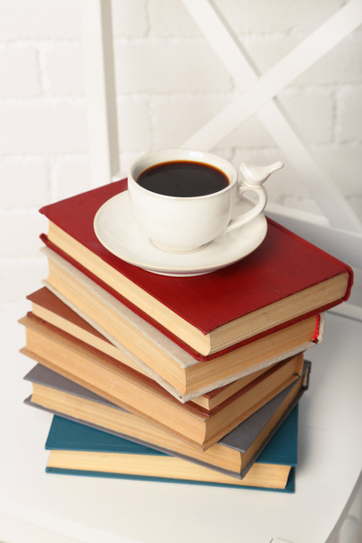 Pile of books with cup of hot drink on the chair on brick wall background - Foto, imagen
