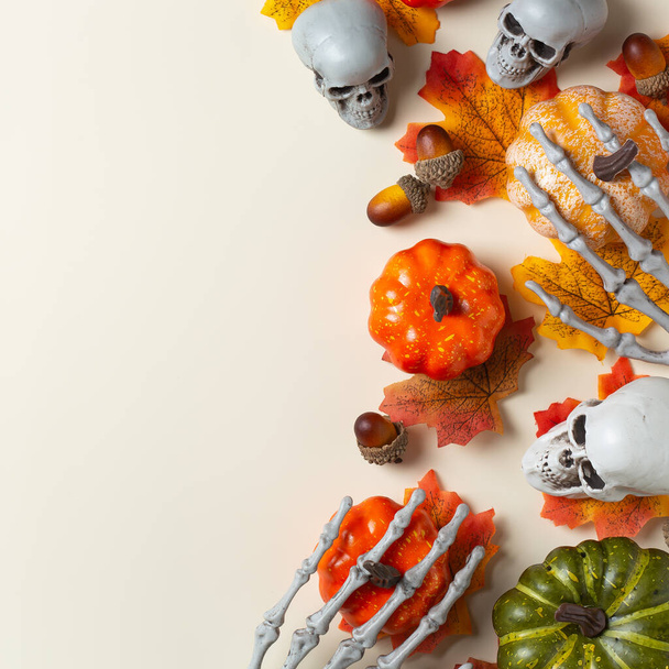 Frohes Halloween, Glückwunschkarte mit Kürbis, Totenköpfen, knöchernen Händen und Blättern. Flache Legekomposition, Kopierraum-Attrappe - Foto, Bild