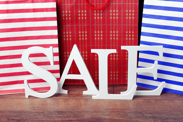 Sale with bags on wooden background - Fotoğraf, Görsel