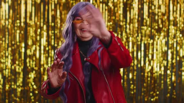 Come here, join us. Welcome. Mature stylish woman showing inviting gesture with hands, ask to join, beckoning to coming, gesturing hello or goodbye. Senior grandmother on shiny disco party background - Footage, Video