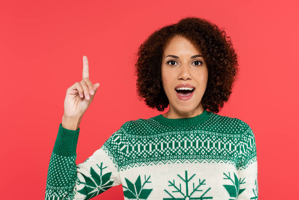 excited african american woman in winter sweater with winter ornament showing idea gesture isolated on red - Fotografie, Obrázek