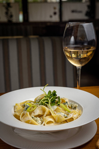 delicious pasta with cheese, greens, sauce in a restaurant - Foto, afbeelding