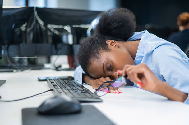 Африканская молодая женщина спит за рабочим столом - Фото, изображение