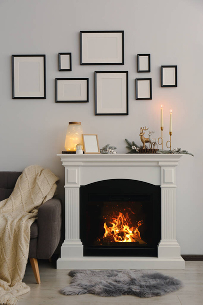 Stylish interior decorations on fireplace near white wall indoors - 写真・画像