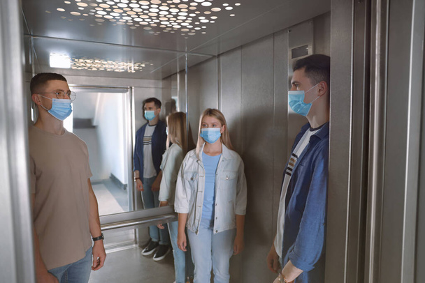 Group of people with face masks in elevator. Protective measure - Foto, Imagen