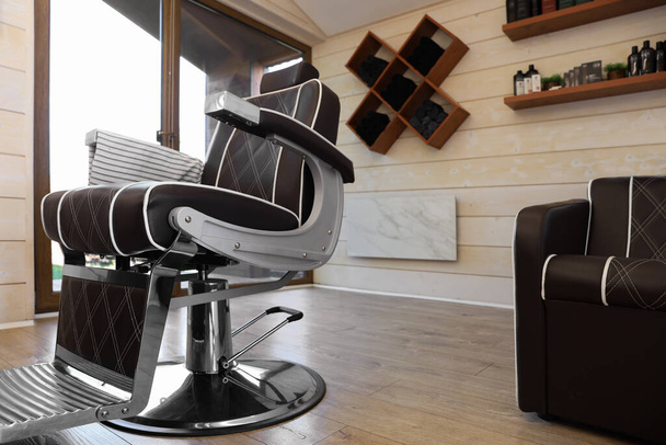 Stylish barbershop interior with professional armchair and modern wash unit - Фото, зображення