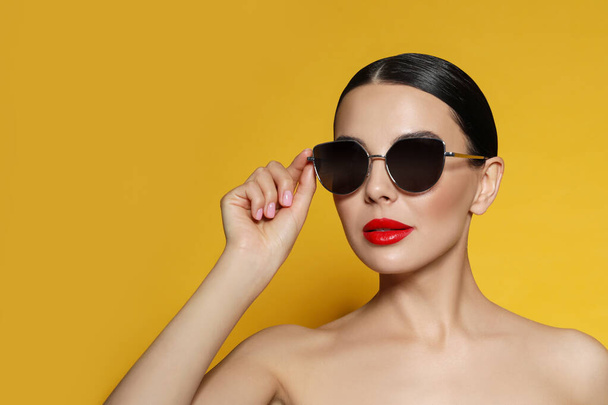 Attractive woman in fashionable sunglasses against orange background. Space for text - Valokuva, kuva