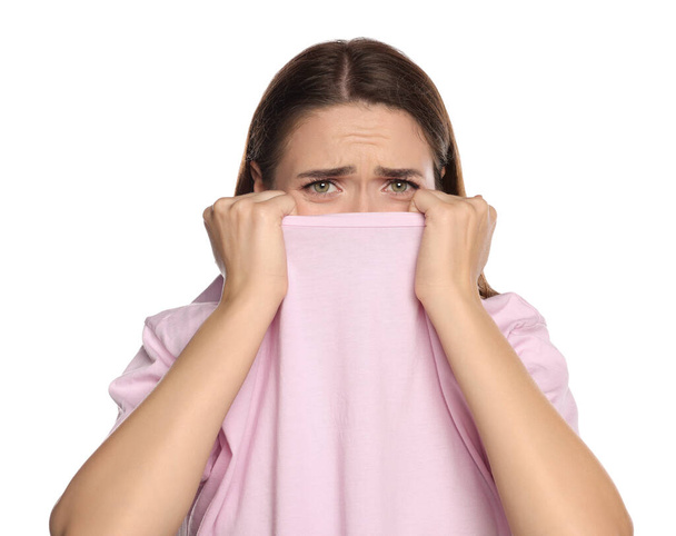Embarrassed young woman covering face with shirt on white background - Photo, Image