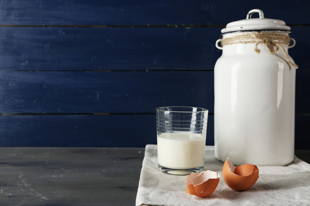 Milk can with glass and eggshell on color wooden background - Zdjęcie, obraz