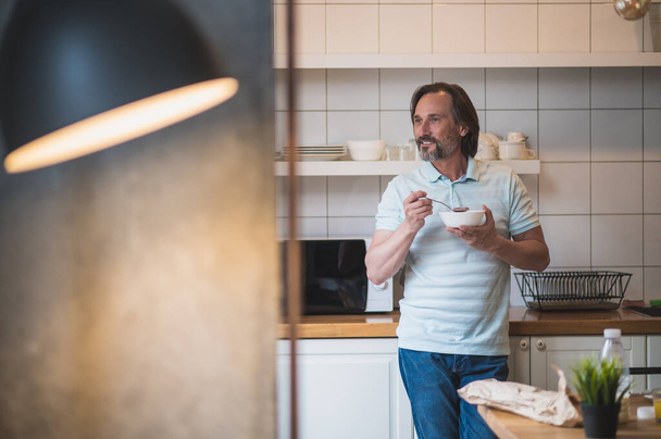 Breakfast at home. Mature man having breakfast and looking contented and peaceful - 写真・画像