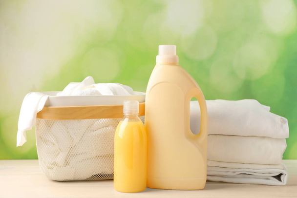 Bottles of laundry detergents and clean clothes on white wooden table - Photo, Image
