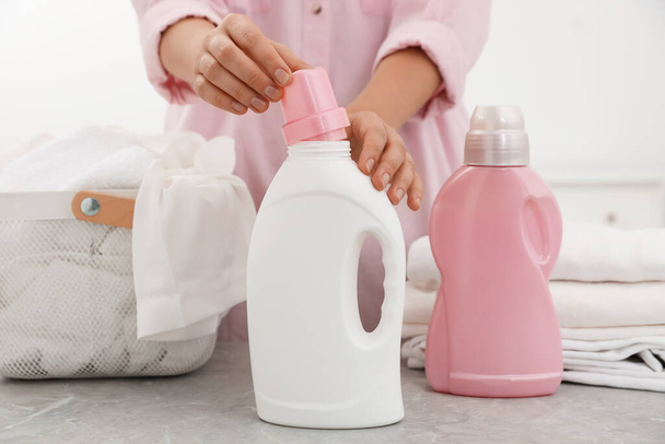 Woman opening bottle of laundry detergent at home, closeup - Foto, immagini