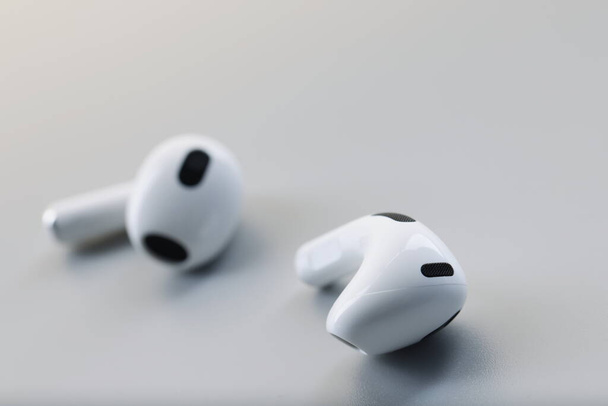 White wireless bluetooth earbuds on a gray background. Fashion phone accessory, headphone noise reduction - Φωτογραφία, εικόνα