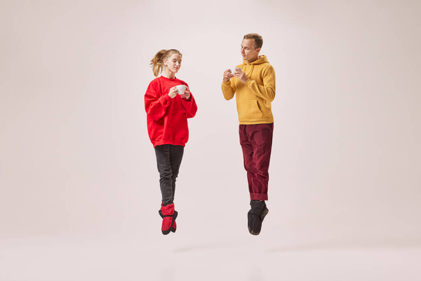 Cozy tea party. Cute young couple of ballet dancers in warm winter homewear drinking, tasting tea isolated on grey background. Retro, vintage, dance, holidays, family concept. Copy space for ad - Foto, afbeelding