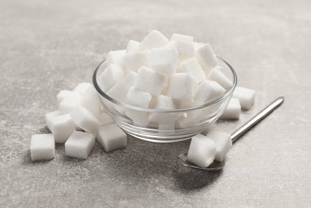 Bowl with sugar cubes served on grey table - Foto, afbeelding