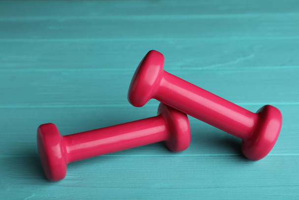 Pink vinyl dumbbells on turquoise wooden table - Photo, image