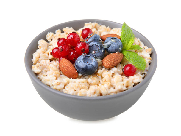 Ceramic bowl with oatmeal, berries. almonds and mint isolated on white - Photo, Image