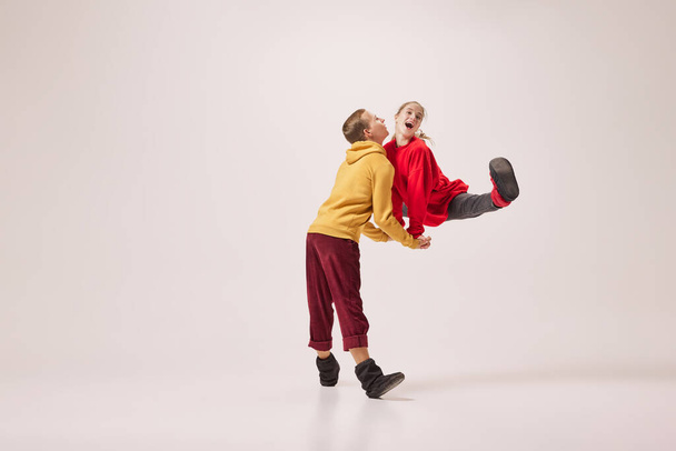 Fun, joy. Emotional flexible young couple of ballet dancers in warm winter homewear dancing isolated on grey background. Retro, vintage, dance, holidays, party concept. Copy space for ad - Photo, image
