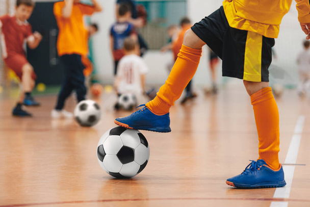 Futball futsal edzés gyerekeknek. Foci edzés gyakorlat. Fiatal focista focilabdával a sportcsarnokban. Sárga egyenruhás játékos. Sport háttér - Fotó, kép