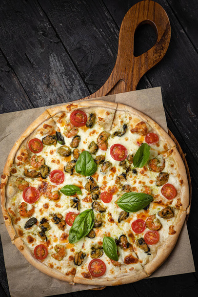 delicious pizza with cheese, greens, sauce in a restaurant - Foto, afbeelding