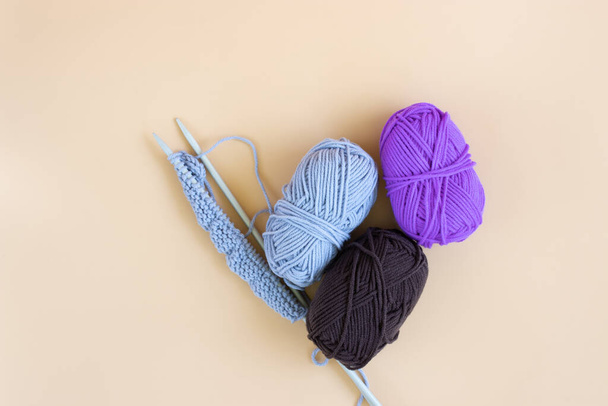 Top view of gray knitting wool and knitting needles on pastel orange background. - Zdjęcie, obraz