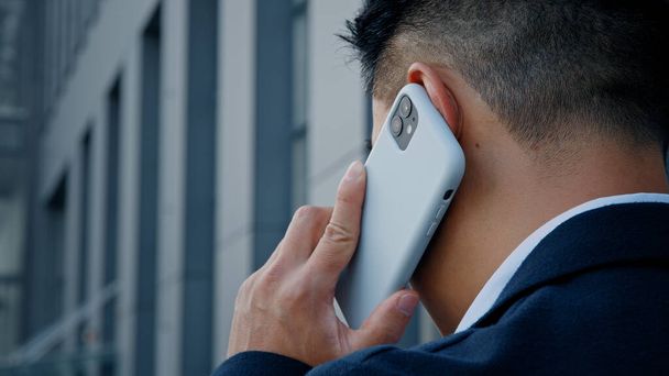 Обратный вид из-за неузнаваемого человека в формальном костюме бизнесмен-продавец разговаривает мобильный телефон на открытом воздухе в городе удаленный виртуальный разговор со смартфоном сотовый разговор вести снаружи - Фото, изображение