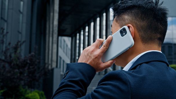 Vissza nézet középkorú ázsiai üzletember vezérigazgató munkáltató vállalkozó főnök hivatalos ember van beszélgetés mobil hívás telefon okostelefon kommunikáció távoli beszélgetés virtuális beszél a városban - Fotó, kép
