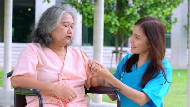 Azjatycki ostrożny opiekun lub pielęgniarka zajmująca się starszym azjatyckim pacjentem na wózku inwalidzkim. Koncepcja szczęśliwej emerytury z opieką opiekuna i Oszczędności i starszego ubezpieczenia zdrowotnego. opieka nad osobami starszymi - Materiał filmowy, wideo