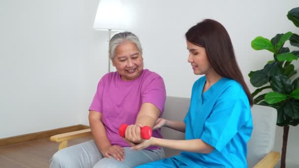 Asian Caregiver nurse doing physical therapy assistance and support teach body and muscle exercises to elderly women. Physical therapy and senior citizens rehabilitation concept. - Filmagem, Vídeo