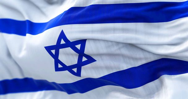 Vista de cerca de la bandera nacional de Israel ondeando en el viento. El Estado de Israel es un Estado del Cercano Oriente frente al Mar Mediterráneo. Fondo texturizado de tela. Enfoque selectivo - Foto, Imagen