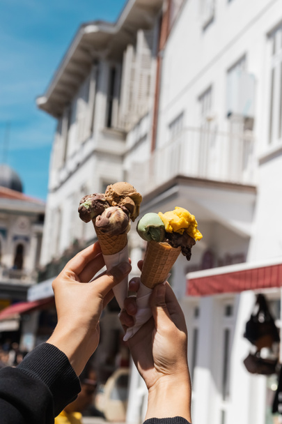 cropped view of woman holding tasty ice cream cones in hands on urban street - 写真・画像