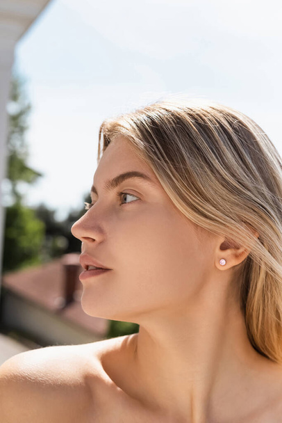 portrait of young blonde woman with bare shoulder looking away - Foto, imagen