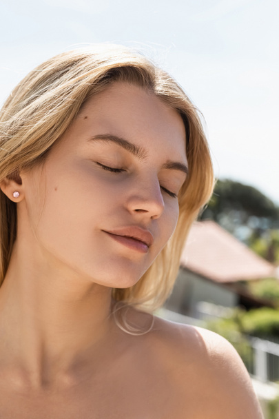 portrait of young blonde woman with bare shoulder and closed eyes in turkey - Foto, imagen